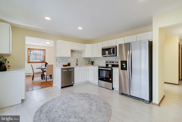 kitchen featuring white cabinetry, sink, backsplash, and appliances with stainless steel finishes