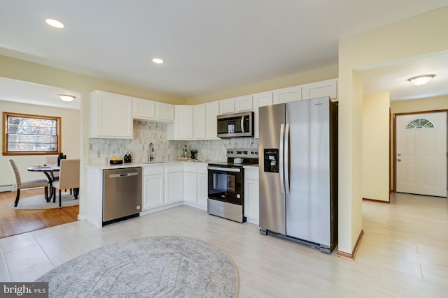 kitchen featuring sink, white cabinetry, tasteful backsplash, a baseboard radiator, and stainless steel appliances