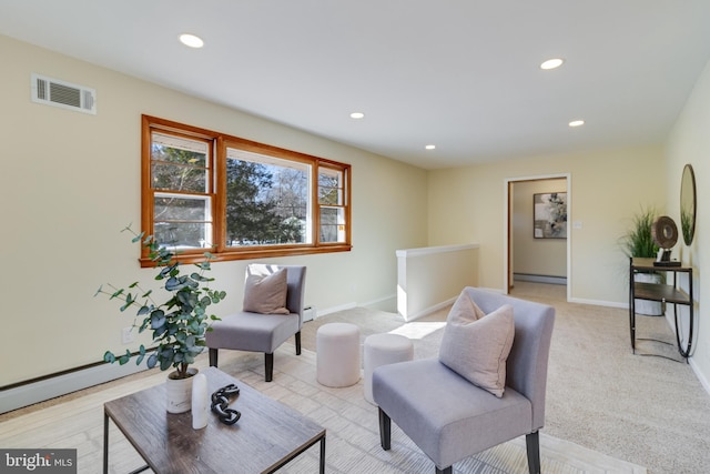 living room with a baseboard heating unit and light colored carpet