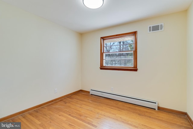 spare room with baseboard heating and light hardwood / wood-style floors