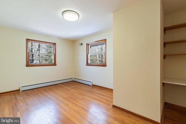 unfurnished room featuring a baseboard heating unit and light wood-type flooring