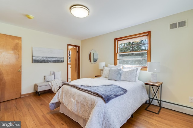 bedroom with a baseboard radiator and light hardwood / wood-style flooring