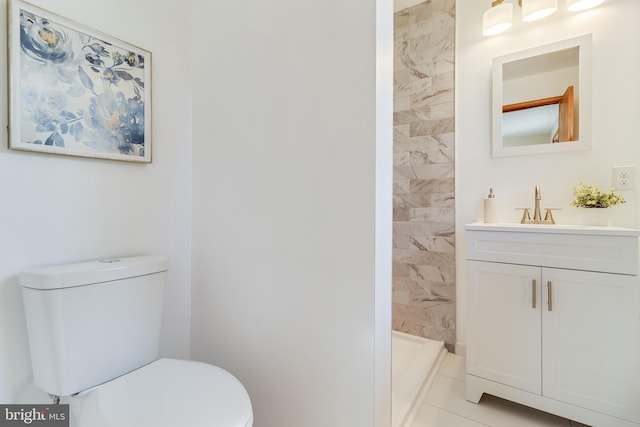 bathroom featuring walk in shower, vanity, tile patterned floors, and toilet