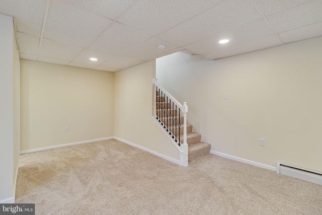 basement with a baseboard radiator, a paneled ceiling, and carpet