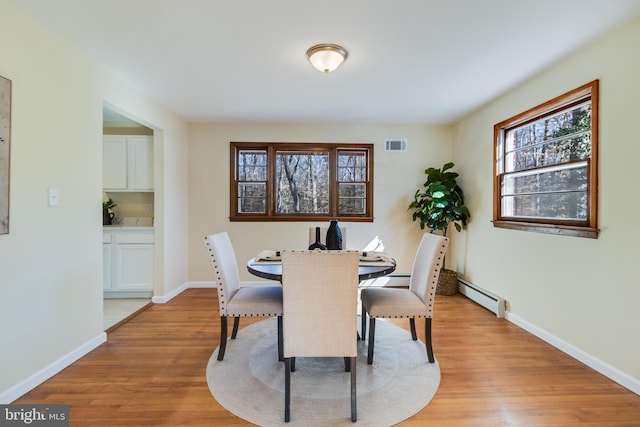 dining room with light wood-type flooring and baseboard heating