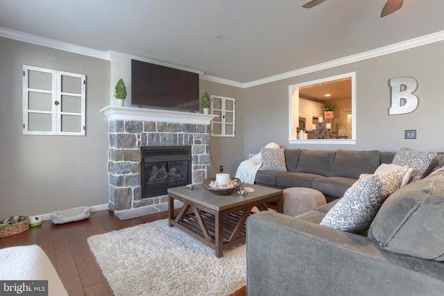 living room with a stone fireplace, crown molding, ceiling fan, and wood-type flooring