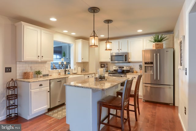 kitchen featuring white cabinets, appliances with stainless steel finishes, a center island, and a breakfast bar