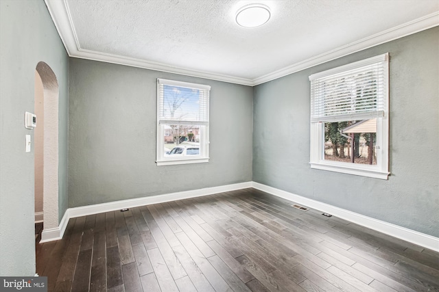 spare room with ornamental molding, dark wood-type flooring, and a wealth of natural light