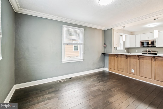 kitchen featuring hanging light fixtures, white cabinetry, ornamental molding, and dark hardwood / wood-style flooring