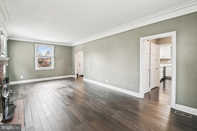 unfurnished living room with a brick fireplace, ornamental molding, and dark hardwood / wood-style floors