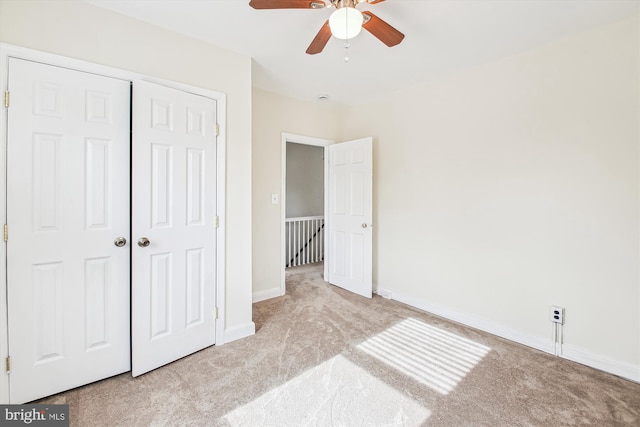 unfurnished bedroom featuring ceiling fan, light colored carpet, and a closet