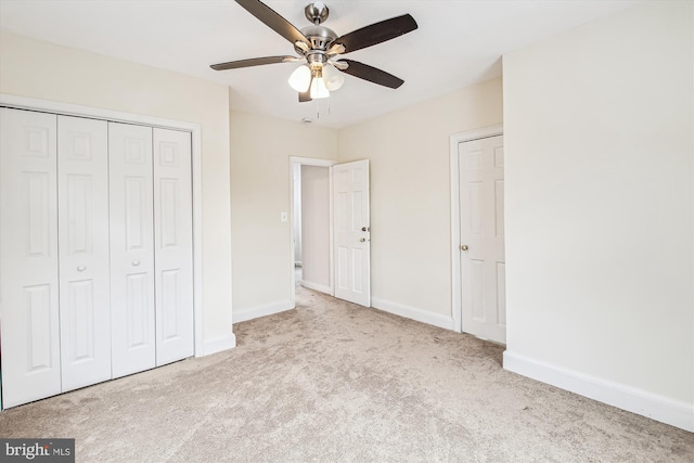 unfurnished bedroom featuring ceiling fan, light colored carpet, and a closet