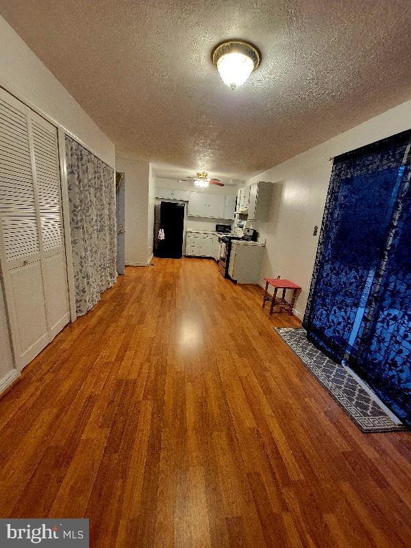 interior space featuring wood-type flooring, a textured ceiling, and ceiling fan