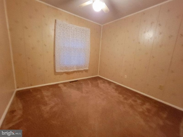 spare room with carpet, ceiling fan, and wood walls