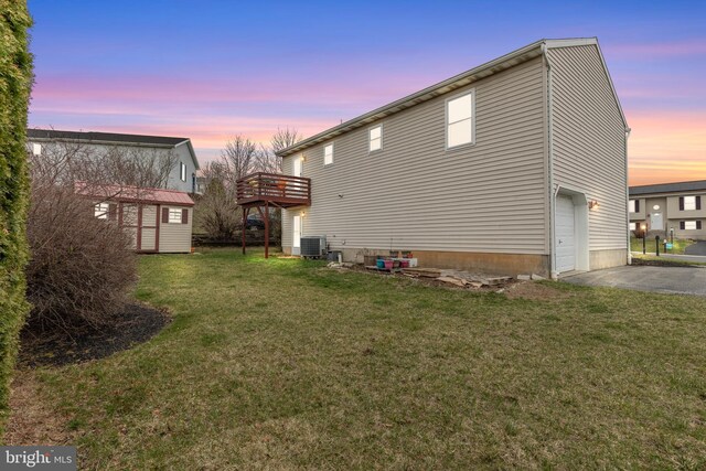1025 Harmony Hl, Lebanon, PA 17046 - back of property at dusk with central AC, a lawn, a garage, an outbuilding, and driveway