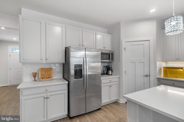 kitchen with decorative light fixtures, tasteful backsplash, light hardwood / wood-style floors, stainless steel appliances, and white cabinets