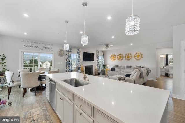 kitchen with hanging light fixtures, white cabinets, sink, and stainless steel dishwasher