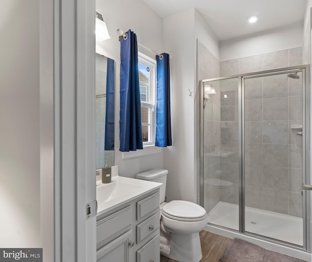 bathroom featuring a shower with shower door, wood-type flooring, toilet, and vanity