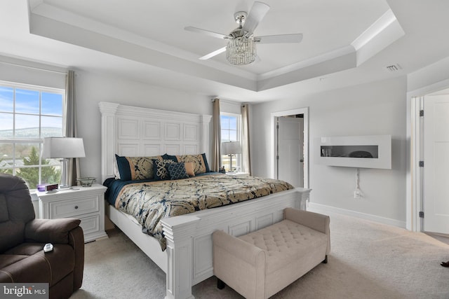 bedroom featuring ceiling fan, light carpet, and a tray ceiling