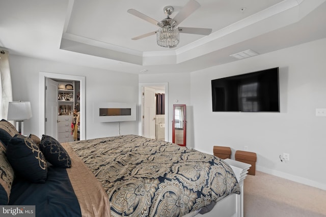 carpeted bedroom with a closet, a walk in closet, connected bathroom, and a raised ceiling