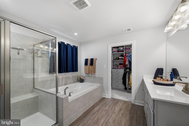 bathroom with wood-type flooring, vanity, and plus walk in shower