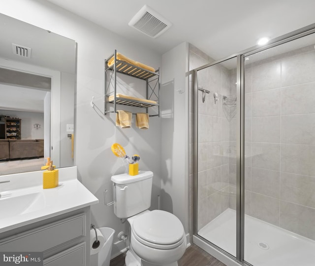 bathroom featuring hardwood / wood-style flooring, an enclosed shower, vanity, and toilet