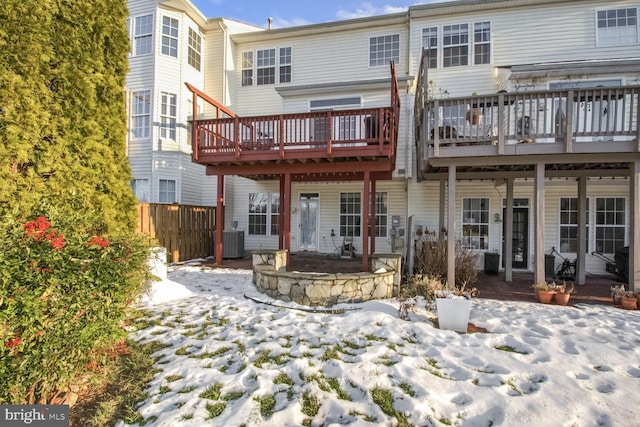 snow covered house with a deck and central air condition unit