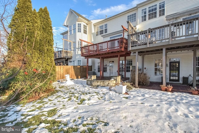 snow covered rear of property featuring a deck