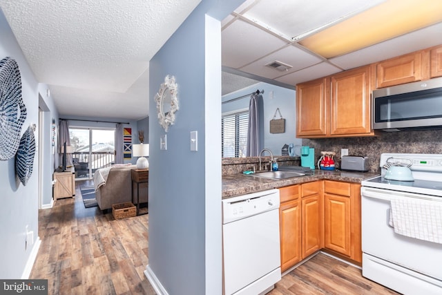 kitchen featuring a paneled ceiling, sink, decorative backsplash, hardwood / wood-style flooring, and white appliances