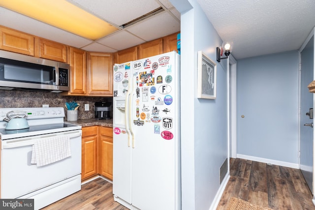 kitchen featuring dark hardwood / wood-style flooring, backsplash, white appliances, and a drop ceiling