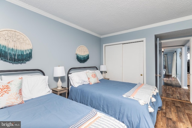 bedroom featuring ornamental molding, dark hardwood / wood-style floors, a textured ceiling, and a closet