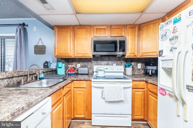 kitchen with tasteful backsplash, white appliances, sink, and a drop ceiling