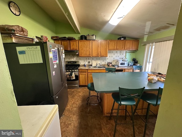 kitchen with a breakfast bar, lofted ceiling, sink, tasteful backsplash, and stainless steel appliances