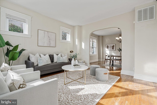 living room with hardwood / wood-style flooring, a healthy amount of sunlight, and an inviting chandelier