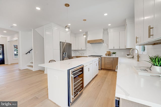 kitchen with pendant lighting, white cabinetry, beverage cooler, a center island, and stainless steel appliances