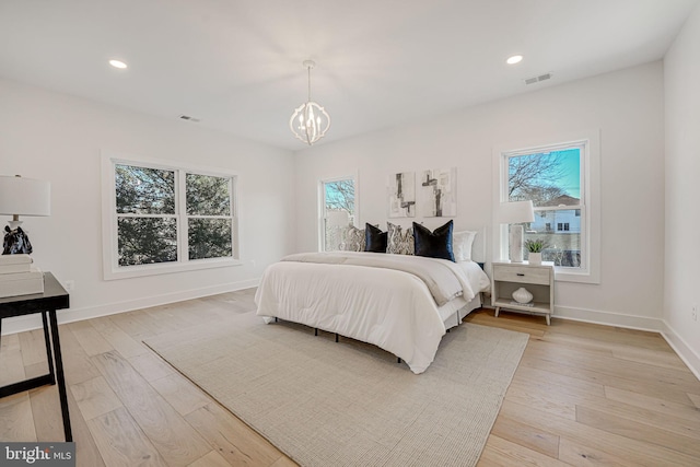 bedroom with multiple windows, light hardwood / wood-style floors, and an inviting chandelier