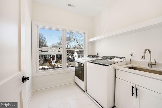 laundry room with cabinets, separate washer and dryer, and sink