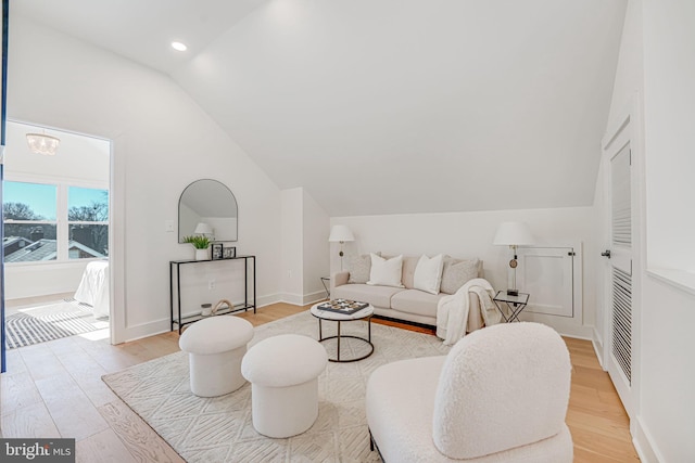 living room featuring vaulted ceiling, a chandelier, and light hardwood / wood-style floors