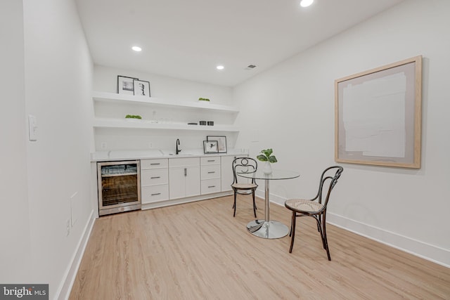 bar featuring white cabinetry, sink, light hardwood / wood-style floors, and beverage cooler