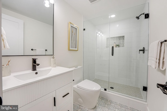 bathroom with vanity, a shower with door, and toilet