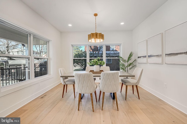 dining area with a notable chandelier, a wealth of natural light, and light wood-type flooring