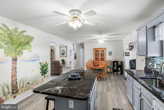 kitchen featuring dishwashing machine, gray cabinetry, dark stone countertops, and sink