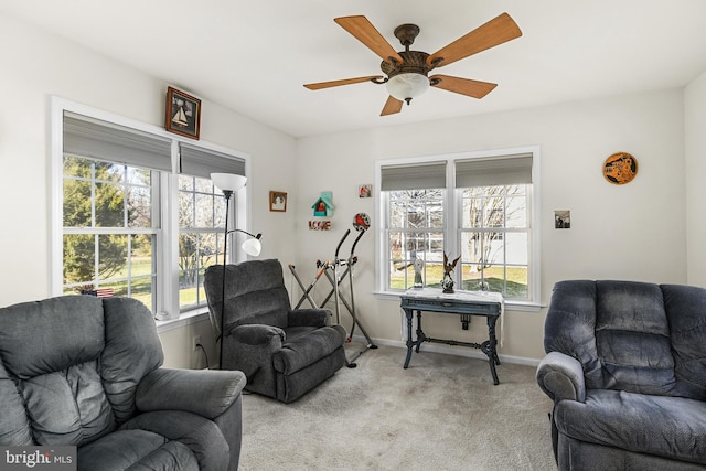 living area featuring a wealth of natural light, ceiling fan, and light colored carpet