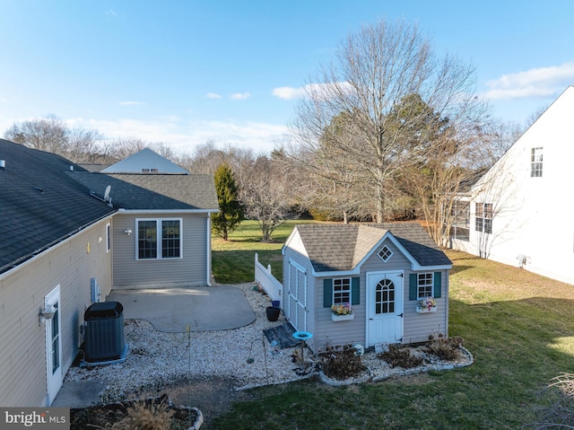 view of side of property featuring a lawn, an outbuilding, a patio, and central AC