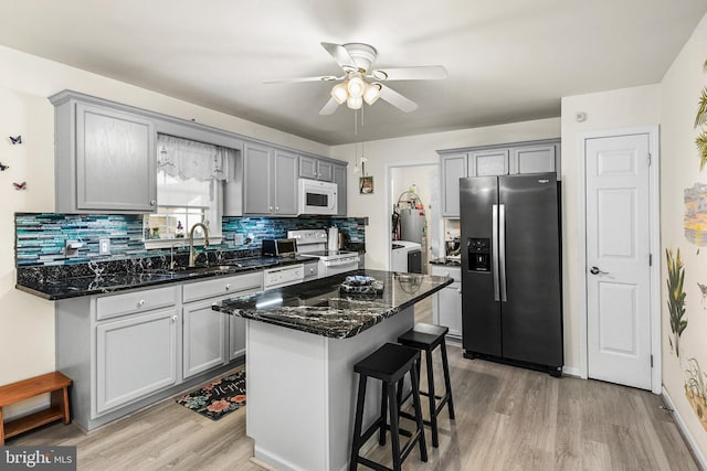 kitchen featuring a center island, range with electric stovetop, dark stone countertops, and stainless steel refrigerator with ice dispenser