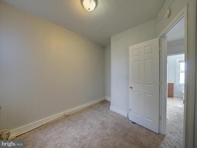 empty room featuring wooden walls and light colored carpet