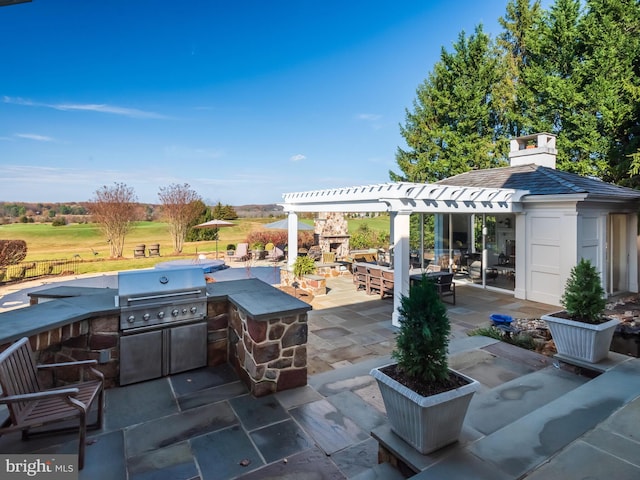 view of patio / terrace featuring an outdoor stone fireplace, a grill, and exterior kitchen