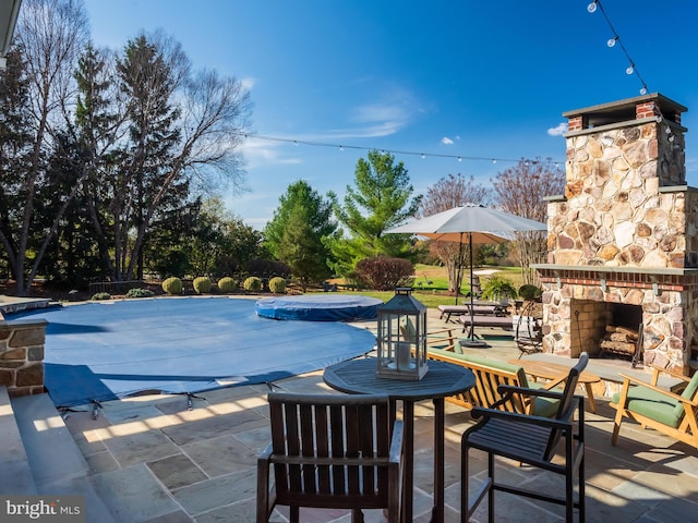 view of pool featuring a patio and an outdoor stone fireplace