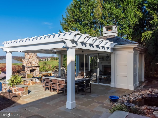 view of patio with an outdoor stone fireplace and a pergola