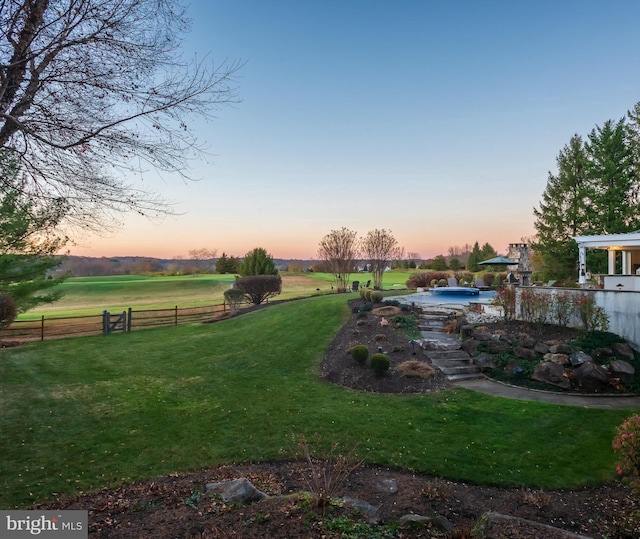 yard at dusk featuring a rural view